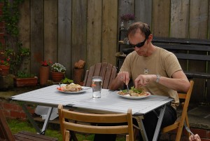 テーブルでナイフとフォークで食事するサングラスの男性