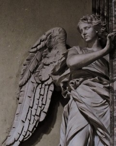 翼の生えた女性の姿で衣を羽織る天使風の石像