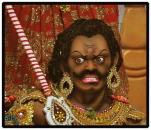 頭パンチパーマで髭を生やし、ピヤスと金の装飾品で飾る、すごい形相のインドの神様風の男性