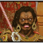 頭パンチパーマで髭を生やし、ピヤスと金の装飾品で飾る、すごい形相のインドの神様風の男性